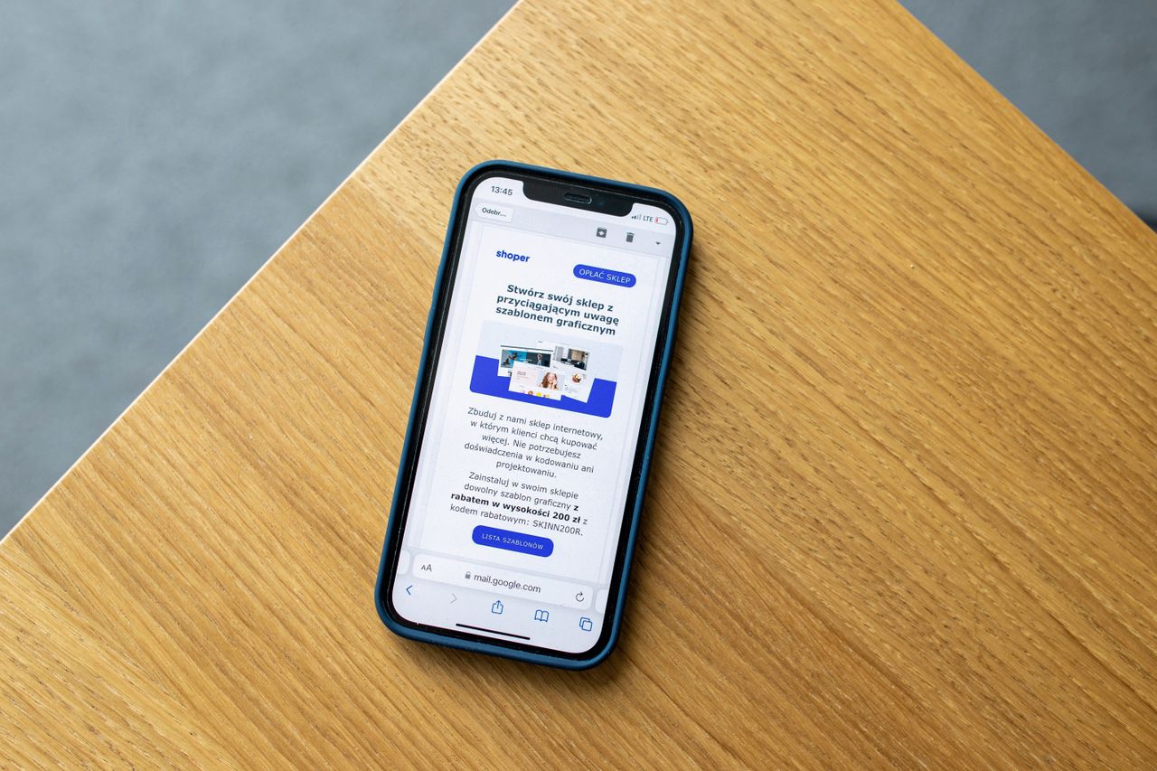 A mobile phone showing an e-commerce interface rests on a wooden surface, representing online shopping technology.